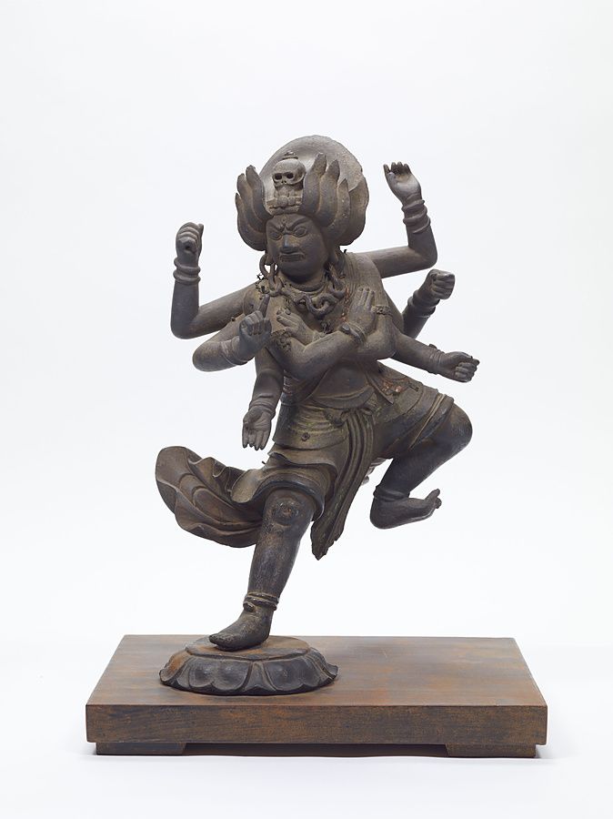 Statuetta lignea di divinità buddhista feroce con molte braccia che danza su un piede sopra un loto