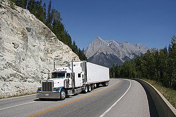 Un camion che sfreccia tra montagne rocciose.