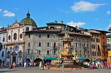 Piazza Duomo a Trento: in primo piano la fontana e sullo sfondo l'edificio con gli storici affreschi.