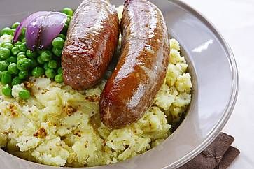 Bangers and mash: salsicce su purè di patate con semi di senape, piselli e cipolla rossa grigliata.