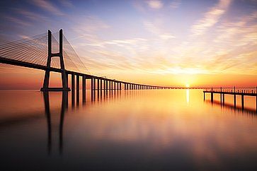 Ponte Vasco da Gama a Lisbona al tramonto riflesso nelle acque calme.