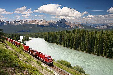 Treno merci lungo il fiume Bow nelle Montagne Rocciose Canadesi.