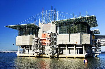 Lisbon Oceanarium sull'acqua, struttura moderna e ampia sotto un cielo azzurro.