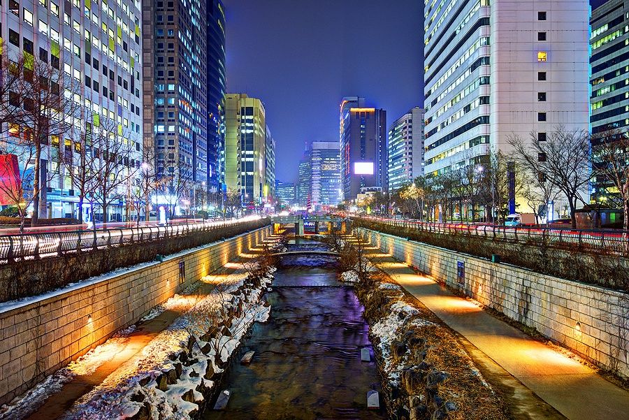 Il torrente Cheonggyecheon a Seoul di notte con grattacieli illuminati.