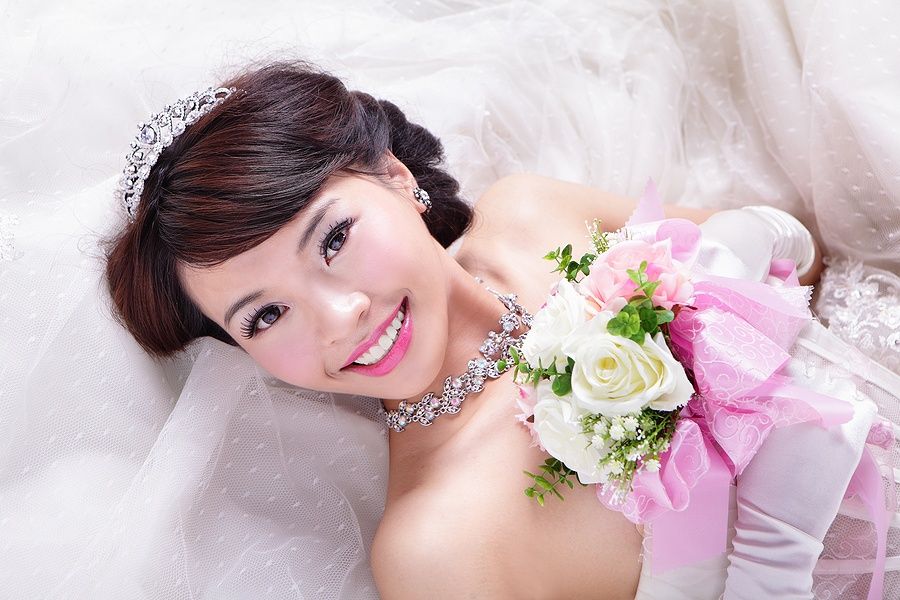 Sposa asiatica sorridente con bouquet di rose