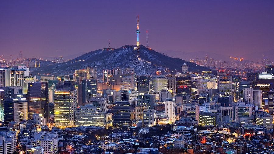 Skyline di Seoul al tramonto con la torre di Seoul e grattacieli illuminati.