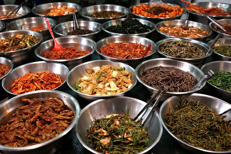 Ciotole metalliche con kimchi e verdure fermentate in un mercato di Suwon.