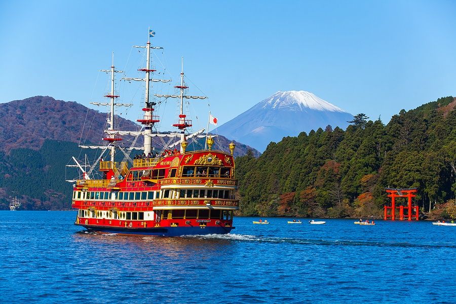 Nave sul lago Ashi con il Monte Fuji e un torii rosso sullo sfondo.