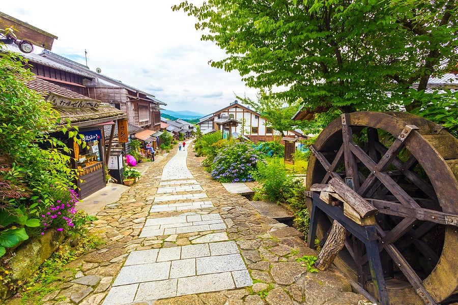 Percorso in pietra a Magome con edifici tradizionali e ruota idraulica.