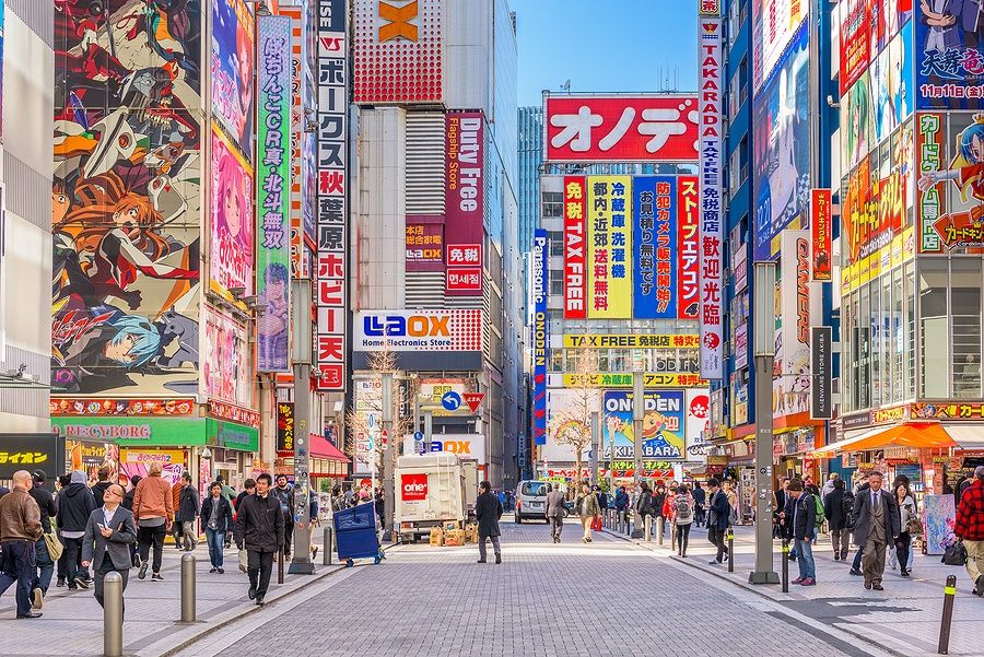 Strada affollata di Akihabara a Tokyo con cartelloni colorati.
