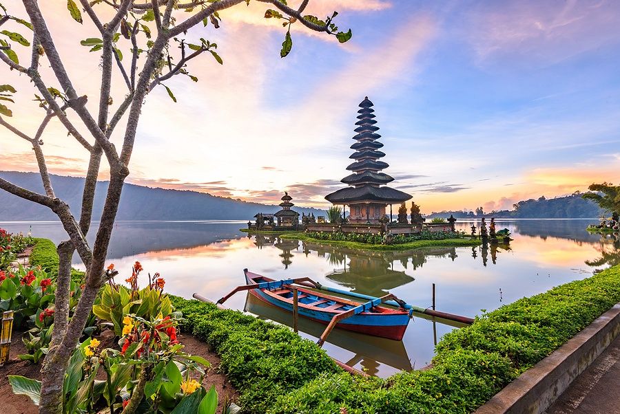 Il tempio Pura Ulun Danu Bratan a Bali al tramonto con una barca in primo piano.