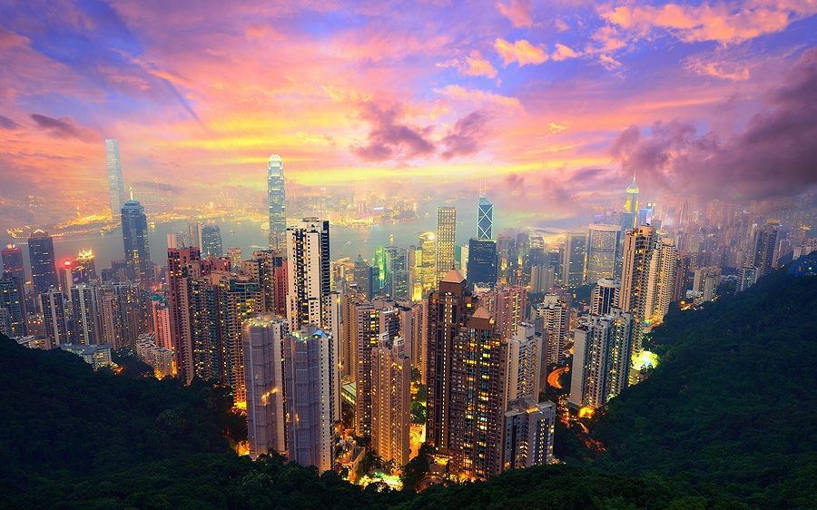 Skyline di Hong Kong dal Victoria Peak al tramonto con grattacieli illuminati.