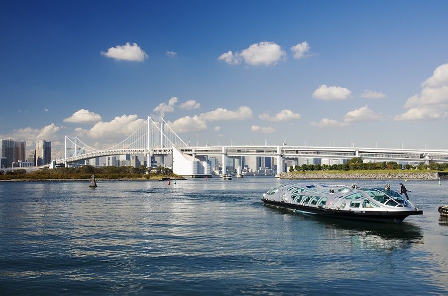 Barca nella Baia di Tokyo con Rainbow Bridge e grattacieli sullo sfondo.
