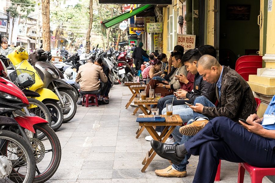 Persone bevono caffè sedute su piccoli sgabelli a Hanoi, Vietnam.