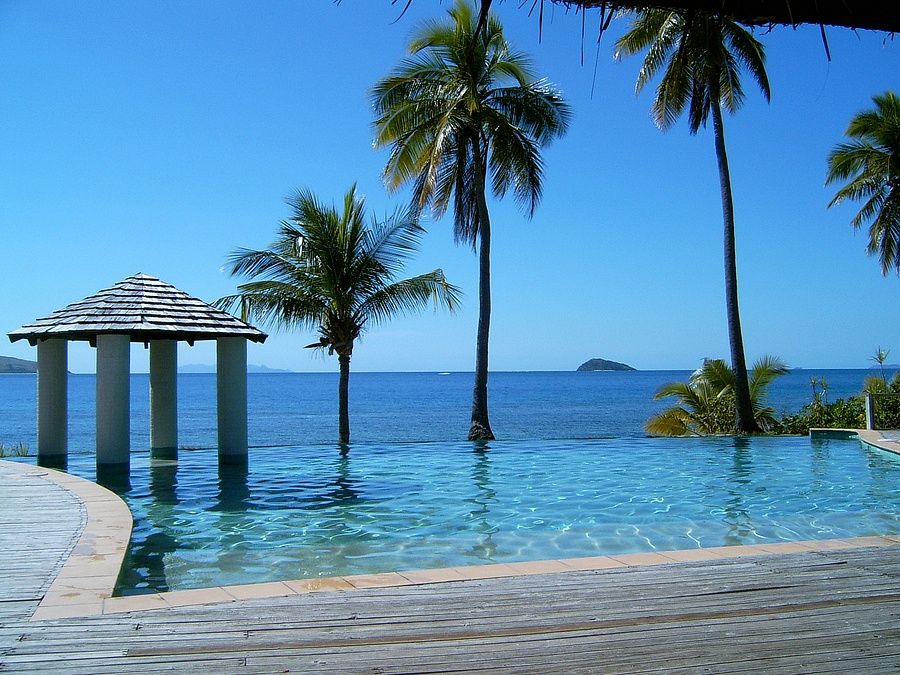 Piscina a sfioro su Mana Island, Fiji, con vista sul mare e palme.