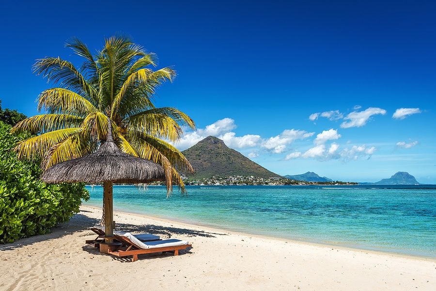 Sdraio e ombrellone sotto una palma su una spiaggia tropicale a Mauritius.