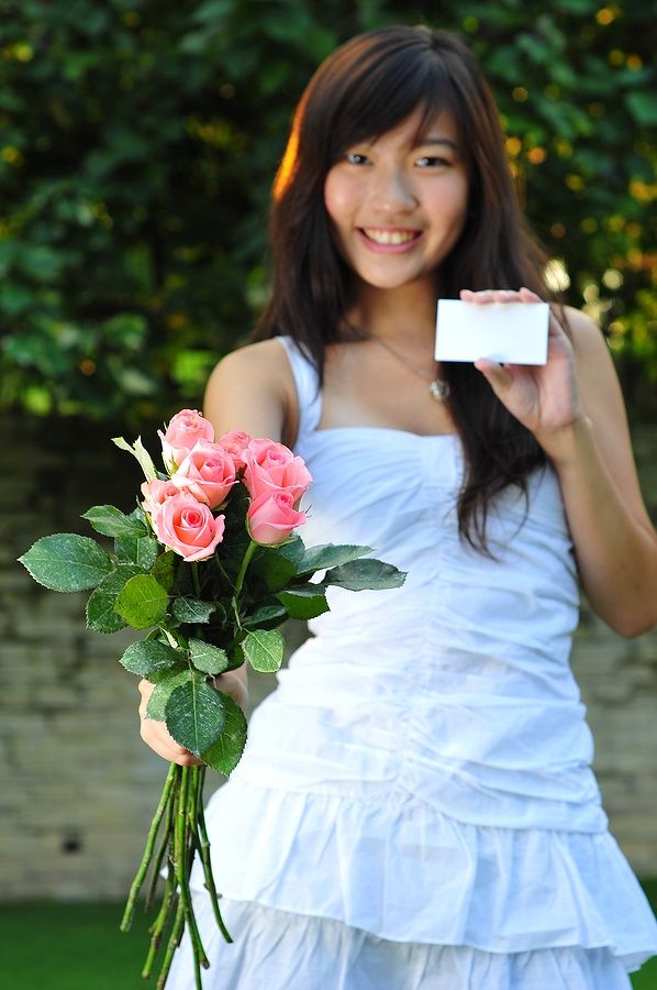 Donna asiatica con bouquet di rose rosa e carta nera.
