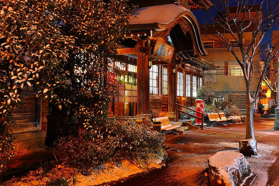 Edificio tradizionale giapponese del Takegawara Onsen innevato di notte a Beppu, Kyushu.