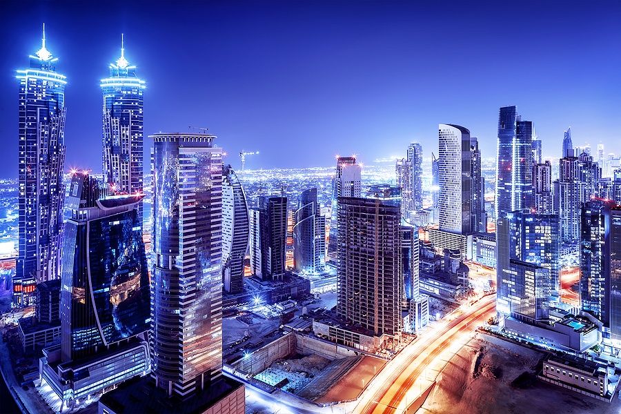 Skyline notturno di Dubai con grattacieli illuminati e strade brillanti.