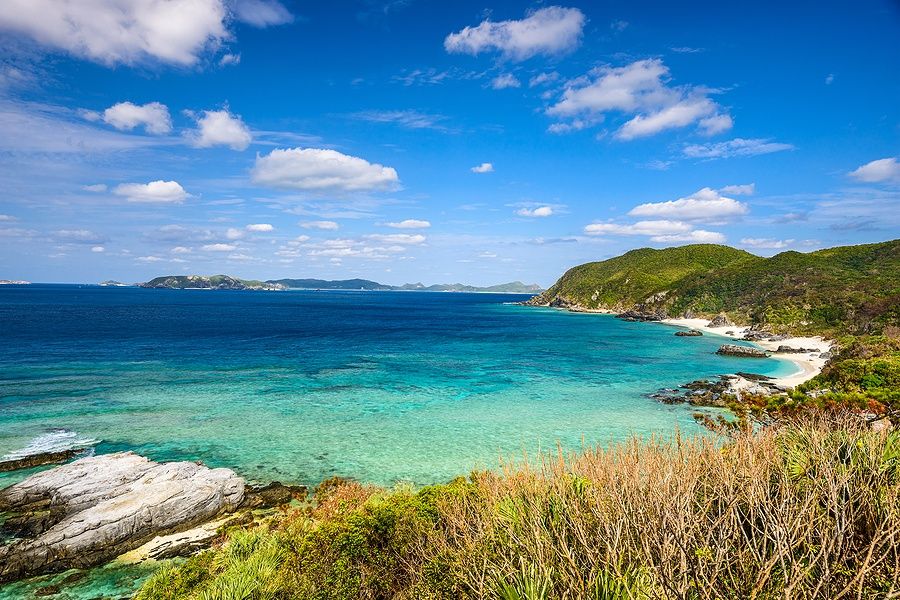 Costa di Tokashiki, Okinawa, con mare turchese e spiagge bianche sotto un cielo blu.