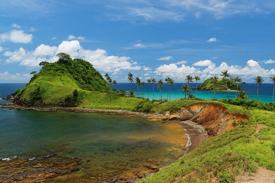 Vista della punta sud-ovest di Nacpan beach con colline verdi e palme.