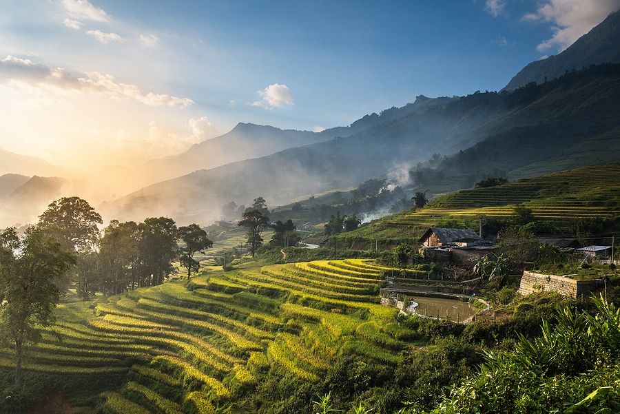 Campi di riso terrazzati al tramonto a Sapa, Vietnam, con montagne sullo sfondo.