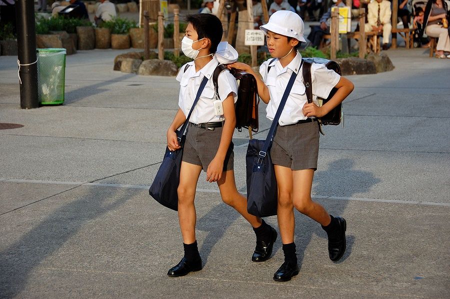Due studenti giapponesi a Tokyo, uno con mascherina.