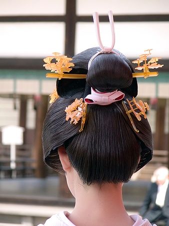 Acconciatura tradizionale di una geisha con ornamenti dorati e dettagli raffinati.