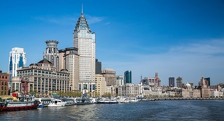 Skyline del Bund a Shanghai, con edifici storici lungo il fiume sotto un cielo azzurro.