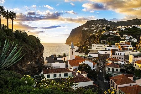 Panorama di Câmara de Lobos al tramonto, con case e oceano sullo sfondo.