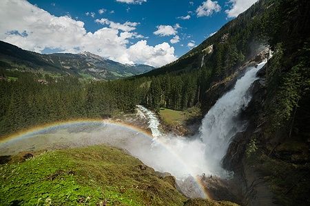 Cascata Krimml in Austria con arcobaleno e montagne sullo sfondo.