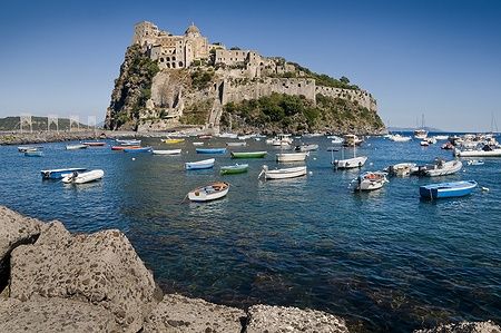 Castello Aragonese a Ischia, circondato da barche nel mare blu.