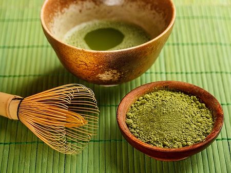 Ciotola di matcha e strumenti per la cerimonia del tè giapponese su tovaglietta verde.