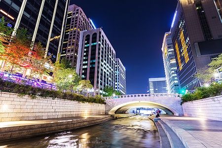 Cheonggyecheon a Seoul di notte con edifici moderni e un corso d'acqua illuminato.