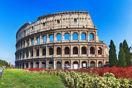 Il Colosseo di Roma con un giardino di fiori colorati in primo piano.