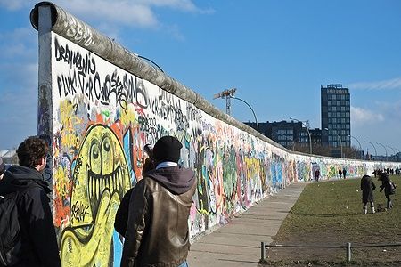 L'East Side Gallery di Berlino con graffiti colorati e persone che osservano.