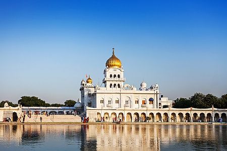 Gurdwara Bangla Sahib con cupola dorata e riflesso sull'acqua.