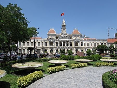 Ho Chi Minh City Hall a Saigon con giardini curati sotto un cielo azzurro.