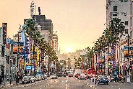 Veduta di Hollywood Boulevard al tramonto con palme e traffico.