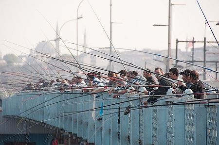 Persone pescano dal ponte di Galata a Istanbul con canne da pesca.