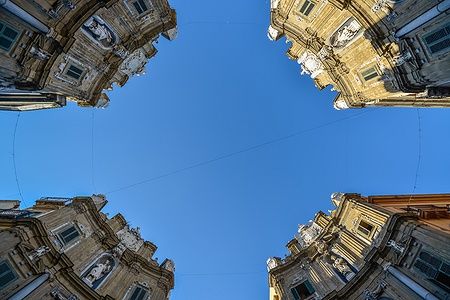 Veduta dal basso dei Quattro Canti di Palermo sotto un cielo blu.