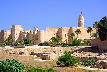Il Ribat di Monastir in Tunisia con cielo azzurro e palme.