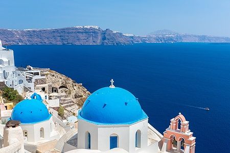 Chiesa ortodossa di Santorini con cupole blu e mare sullo sfondo.