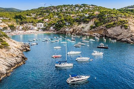 Barche ancorate nella baia di Ses Salines a Ibiza, con la costa sullo sfondo.