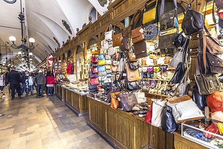 Interno del Sukiennice a Cracovia con bancarelle di artigianato e borse colorate.
