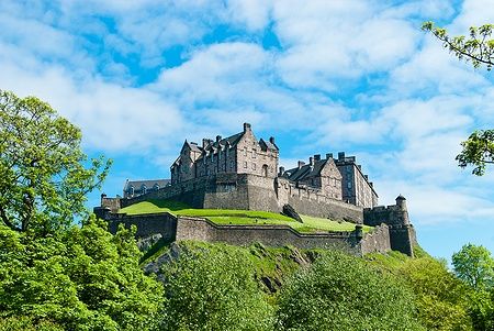 Il Castello di Edimburgo su una collina verde sotto un cielo azzurro.