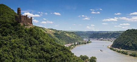 Vista della Valle del Reno con il Castello Maus e il fiume in una giornata soleggiata.