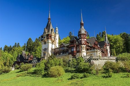 Castello di Peles a Sinaia, Romania, immerso nel verde sotto un cielo blu.