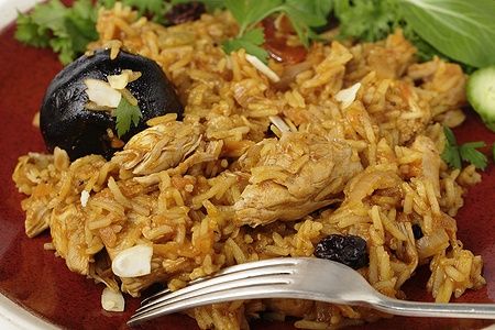 Chicken kabsa saudita con uvetta e mandorle tostate su un piatto.
