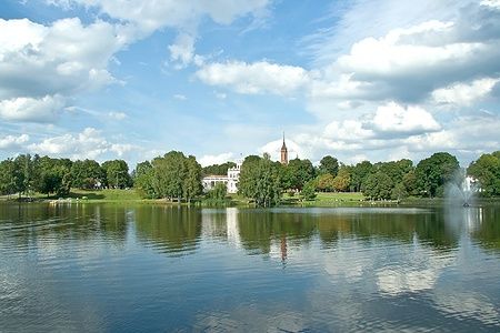 Vista di Druskininkai dal lago con edifici e vegetazione riflessi nell'acqua.